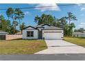 Inviting home with white exterior, dark accents, a long driveway, and well-manicured lawn at 6291 Sw 133Rd Street Road, Ocala, FL 34473