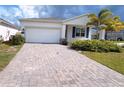 Long, brick paver driveway leading to a single-Gathering home with a two-car garage and tropical landscaping at 6300 Chirpine Ln, St Cloud, FL 34771