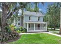 Inviting two-story home with a covered front porch, mature trees, and a well-manicured lawn creates a welcoming atmosphere at 1021 S Elm Ave, Sanford, FL 32771