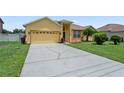 View of the home with long driveway, two-car garage, and manicured lawn at 1457 Teal Dr, Kissimmee, FL 34759