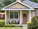 Inviting covered porch with seating, a wreath, and manicured bushes leading to the front door at 2009 E Grant St, Orlando, FL 32806