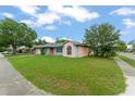 A quaint single-story house with lush green lawn and charming pink exterior nestled in a quiet, tree-lined neighborhood at 2309 Cilantro Dr, Orlando, FL 32837