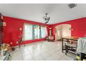 A bright living room with tiled floor, red accent walls, and large windows that fill the space with natural light at 2309 Cilantro Dr, Orlando, FL 32837