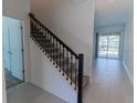 Inviting entryway with a staircase featuring dark wood railings, carpeted steps, and tile flooring at 2460 Reading Trl, Kissimmee, FL 34746