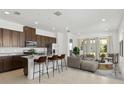 Open-concept living space features a modern kitchen with island seating and a comfortable living area with ample natural light at 2571 Yellow Brick Rd, St Cloud, FL 34772