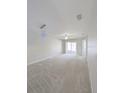 An empty living room boasts neutral paint, carpet flooring, and sliding glass doors to a balcony at 2816 Club Cortile Cir # A, Kissimmee, FL 34746