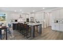 Open kitchen boasts white cabinets, stainless steel appliances, large island, and wood floors at 3004 Water Clover Ct, Apopka, FL 32712
