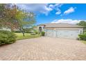 Elegant home with a three-car garage and a brick paver driveway surrounded by manicured landscaping at 3531 Oriskany Dr, Orlando, FL 32820