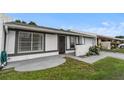 Single-story home boasts white exterior with gray trim, a secure front gate, and well-manicured landscaping at 1184 Calanda Ave, Orlando, FL 32807