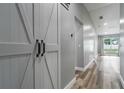 Bright hallway featuring light gray walls, luxury vinyl plank flooring, and modern farmhouse-style sliding barn door at 1184 Calanda Ave, Orlando, FL 32807