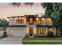 Captivating two-story house illuminated at dusk, features a brick driveway and a neatly maintained front lawn at 1620 S Eola Dr, Orlando, FL 32806