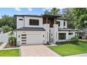 Charming two-story house with a modern facade, featuring a well-kept lawn and brick driveway leading to the garage at 1620 S Eola Dr, Orlando, FL 32806