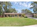 Beautiful one-story brick home with a lush green lawn, mature trees, and inviting curb appeal at 223 Royal Oaks Cir, Longwood, FL 32779