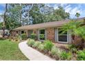 Close-up view of a brick home featuring lush landscaping, walkway and well-maintained greenery at 223 Royal Oaks Cir, Longwood, FL 32779