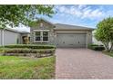 Charming home featuring a stone facade, brick driveway, manicured lawn, and a two-car garage at 2829 Red Alder Blvd, Ocoee, FL 34761