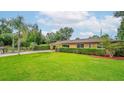 Single-story home with mature trees, lush green lawn, and manicured hedges adding curb appeal at 6430 Yellowstone St, Orlando, FL 32807