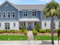 Inviting blue and white two-story home with a well-manicured lawn, walkway, and beautiful landscaping at 8427 Modiano St, Orlando, FL 32827