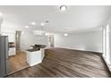 Open-concept kitchen and living area with hardwood floors, white cabinets and a breakfast bar at 109 Greentree Ln, Yalaha, FL 34797