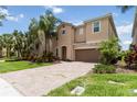 Charming two-story home with a brick driveway, well-manicured lawn, and lush landscaping at 12286 Regal Lily Ln, Orlando, FL 32827