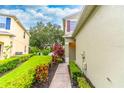 Inviting home entrance featuring a walkway lined with vibrant landscaping and lush green lawn at 1356 Scarlet Oak Loop, Winter Garden, FL 34787