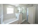 Bright bathroom featuring a tub with marble tile surround and glass-enclosed shower at 14308 Abington Heights Dr, Orlando, FL 32828
