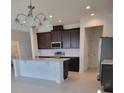 Bright kitchen with stainless steel appliances, an island with bar seating, and dark brown cabinets at 1855 Church Lake St, Groveland, FL 34736