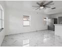 Sunlit living area with tile floors, ceiling fan, and a stainless steel refrigerator visible in the kitchen area at 306 Modest St, Lakeland, FL 33805
