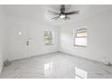 Bright living room featuring new white tile flooring, a modern ceiling fan, and natural light from the windows at 306 Modest St, Lakeland, FL 33805