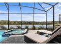 Relaxing pool area with a spa and lounge chairs under a screened enclosure with lake views at 4185 Paragraph Dr, Kissimmee, FL 34746