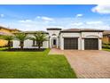 Beautiful white home with tile roof, well-manicured lawn, and brick driveway at 7733 Pointe Venezia Dr, Orlando, FL 32836