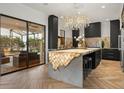 Modern kitchen featuring a unique, illuminated kitchen island, dark cabinets, and stylish chandelier at 7733 Pointe Venezia Dr, Orlando, FL 32836