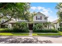 Beautiful two-story home with a cozy front porch, red shutters, and mature trees providing ample shade at 8113 Key West Dove St, Winter Garden, FL 34787