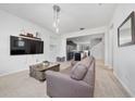 Cozy living room with neutral carpet, TV, open floor plan and modern lighting at 9115 Longship Aly, Orlando, FL 32832