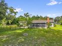 Picturesque backyard featuring a fenced yard, screened porch, and cozy fire pit area at 1008 Bay Ave, Lake Wales, FL 33859