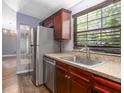 Functional kitchen with stainless steel appliances, wood cabinets, and a window over the sink at 13010 Plum Lake Cir, Minneola, FL 34715