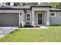 Close up of the front door and two car garage of this single-story gray house at 1868 14Th St, Orange City, FL 32763