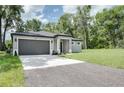 One-story home with a gray exterior, dark roof, and a paved driveway leading to an attached two-car garage at 1868 14Th St, Orange City, FL 32763