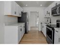 Modern kitchen with white cabinets, stainless steel appliances, and wood-look flooring at 4420 Lake Lawne Ave, Orlando, FL 32808
