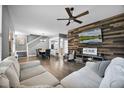 Open-concept living space with wood floors, a wood accent wall, neutral sofa, and adjacent dining area at 14202 Nell Dr, Orlando, FL 32832