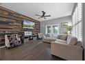 Comfortable living room with a wood accent wall, ceiling fan, neutral sofa and a view of the backyard at 14202 Nell Dr, Orlando, FL 32832