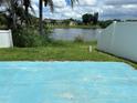 Backyard view featuring a blue patio area and a tranquil pond surrounded by lush greenery at 2149 Mallard Creek Cir, Kissimmee, FL 34743