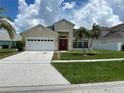 Charming home with a well-maintained lawn, palm trees, a two-car garage, and a vibrant red front door at 2149 Mallard Creek Cir, Kissimmee, FL 34743