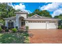 Home exterior featuring a three-car garage, lush landscaping, and a brick driveway at 216 Homestretch Blvd, Deland, FL 32724