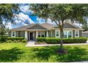 Charming single-story home featuring a well-manicured lawn, mature tree, and neutral-toned facade at 2781 Sand Oak Loop, Apopka, FL 32712