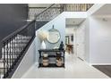 Elegant entryway with tile flooring, a staircase with black iron railings and a decorative console table at 4064 Sunny Day Way, Kissimmee, FL 34744