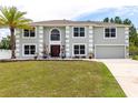 Charming two-story home with a palm tree, green lawn, and well manicured landscaping at 4064 Sunny Day Way, Kissimmee, FL 34744
