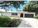 Well-maintained single-story home with fresh white paint, a two-car garage, and mature trees at 5912 Altec Rd, Orlando, FL 32808