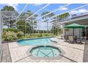 A screened-in pool and hot tub, surrounded by brick pavers with view of the golf course in the background at 856 Bentley Green Cir, Winter Springs, FL 32708