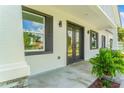 Covered front porch featuring a double door entry, dark shutters, and a small potted plant at 1006 Linkside Ct, Apopka, FL 32712
