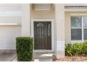 Close-up of front door with sidelight, framed by light-colored siding, trimmed bushes and brick-paver walkway at 10299 Cypress Knee Cir, Orlando, FL 32825